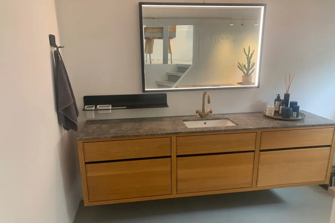 El piso del aseo está cubierto con microcemento de tonalidad gris profundo.